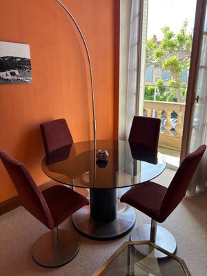 a glass table and chairs in a room with orange walls