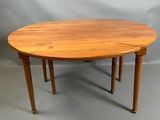 une table de salle à manger ovale avec quatre pieds et un plateau en bois