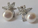 une paire de boucles d'oreilles en perles et diamants posées sur un fond blanc