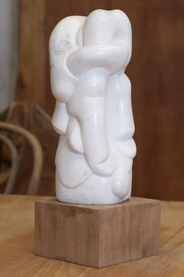 une statue blanche représentant un éléphant, posée sur un socle en bois