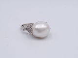 a white pearl and diamond ring on a white surface