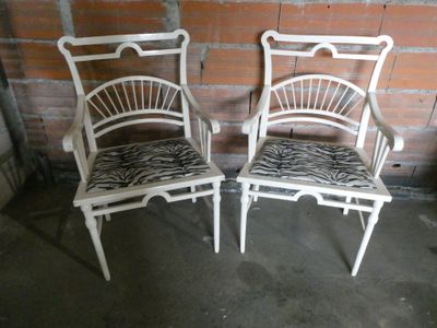 deux chaises blanches avec des coussins à motif zébré devant un mur de briques
