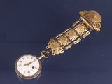 une horloge dorée entourée d'une chaîne, posée sur un fond bleu