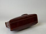 the brown leather toilet bag is sitting on a white surface