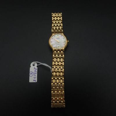 un gros plan d'une montre-bracelet en or sur laquelle est accrochée une étiquette