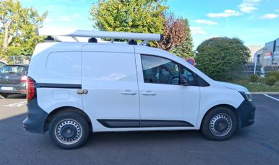 a white van parked in a parking lot with a surfboard on the roof