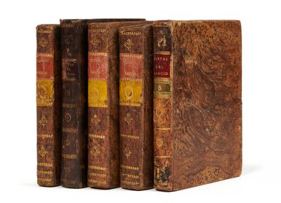 trois vieux livres posés l'un sur l'autre sur une surface blanche