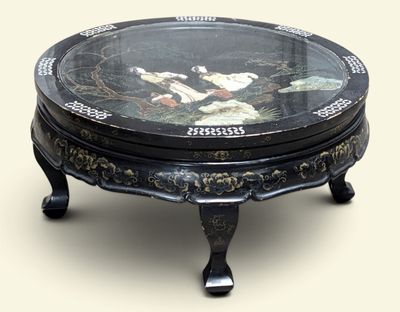 a black table with a glass top with a painting on it