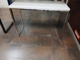 une table blanche avec un plateau en verre dans une pièce