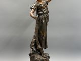 une image représentant une statue en bronze d'une femme tenant un oiseau dans la main