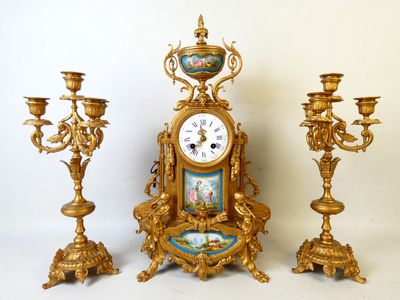 une horloge et trois bougeoirs placés les uns à côté des autres
