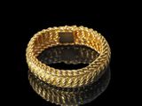 a close up of a gold bracelet on a black surface