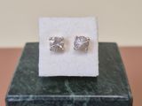 a pair of silver earrings sitting on top of a marble block