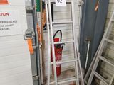 une échelle appuyée contre un mur, à côté d'un extincteur