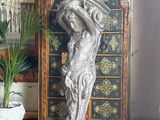 a statue of a woman holding a hat on top of a chest of drawers