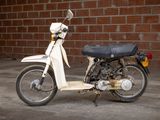 a white motor bike parked in front of a brick wall