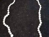 un gros plan d'un collier composé de perles blanches sur un fond noir