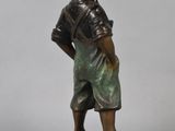 bronze statue of a boy standing on a rock with his hands in his pockets