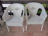 une paire de chaises en osier blanc posées sur une terrasse en briques