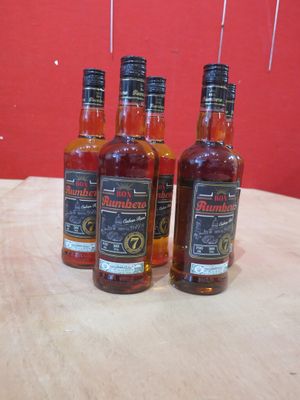 trois bouteilles de whisky sont posées sur une table devant un mur rouge
