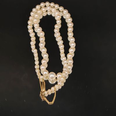 un collier de perles blanches avec un fermoir en or