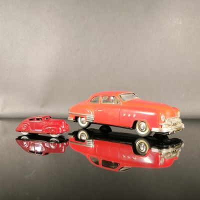une petite voiture rouge et une autre petite voiture rouge posées sur une surface noire