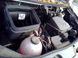 a car engine with its hood open and a tank in the trunk