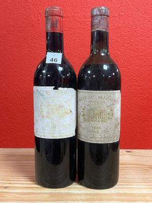 two bottles of wine on a table with a red wall in the background