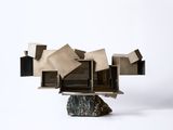 a sculpture made out of books and a rock on a white surface