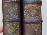 two old books stacked on top of each other on a table