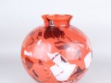 a red vase that has a lot of small pieces of paper on it