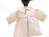 une poupée qui porte une blouse blanche et un chapeau