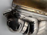 a silver object on a white surface with a dog on it