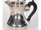 une cafetière ancienne en argent avec une poignée noire sur fond blanc
