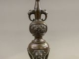 a bronze vase that is on a stand on a white background