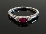 a close up of a ruby and diamond ring on a black surface