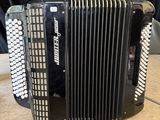 an accordion sitting on top of a wooden table next to a black curtain