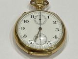 a gold pocket watch sitting on a white surface