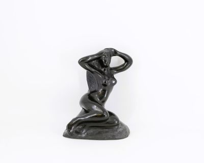 une statue représentant une femme assise sur un rocher, les mains sur la tête