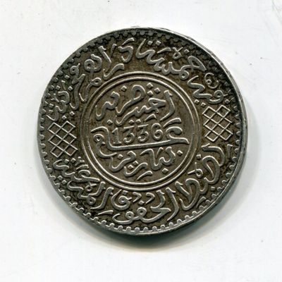 une vieille pièce d'argent comportant un motif sur un fond blanc