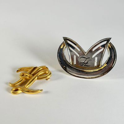 KARL LAGERFELD, réunion de deux broches, l'une couleur métal…
