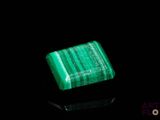a close up of a green stone on a black surface