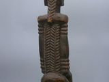 an old wooden statue of a man sitting on a stool