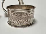 a silver cup with a handle on a white table