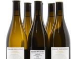 trois bouteilles de vin posées les unes à côté des autres sur une surface blanche