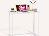 un bureau blanc sur lequel se trouvent un ordinateur portable et une lampe