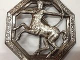 une image représentant une broche en métal sur laquelle figure un homme à cheval