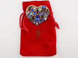 a red velvet bag with a heart shaped brooch on it