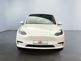 a white tesla model s parked in a room with a black floor
