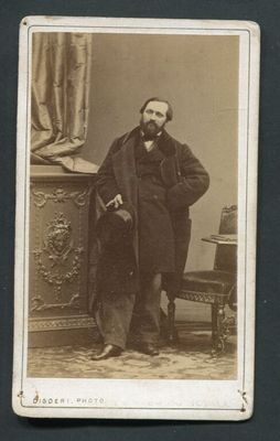 une vieille photo d'un homme vêtu d'un manteau et muni d'une canne